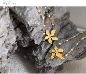 Dettaglio del ciondolo a fiore dorato opaco con perle bianche sulla collana