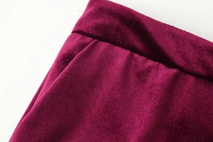 Detailed macro view of the waistband and luxurious burgundy velvet fabric texture