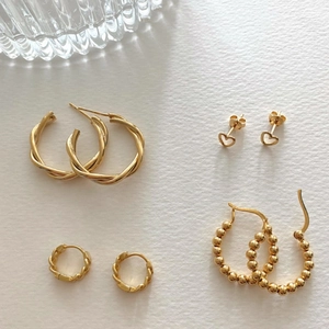 Flat lay of 925 sterling silver gold earrings including heart studs and twisted hoops