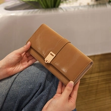 Detailed view of a brown glossy PU leather clutch with elegant rectangular gold buckle