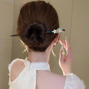 Detail of vintage flower hair stick with pearls and green jade disc in an elegant updo
