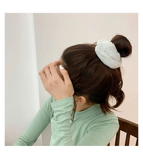 Close-up of a soft white faux rabbit fur hair scrunchie on a model bun hairstyle