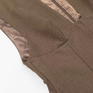 Détail macro d'une robe tissée marron montrant coutures fines, doublure satin et zip