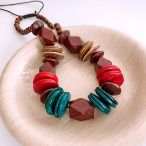 Detail of bohemian necklace with colorful wood beads and turquoise discs on ceramic tray
