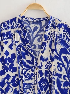 Detail view of V-neckline and button-down closure on blue floral printed long sleeve blouse