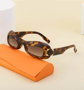 Tortoiseshell oval sunglasses with gradient brown lenses and a bright orange folding case