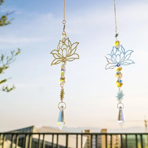Golden and silver lotus suncatchers with crystal prisms hanging against the bright sky