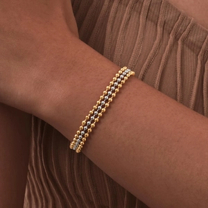 Detail of three-layer gold and silver beaded chain bracelet worn on a female wrist