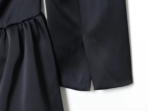 Détail de la robe courte noire avec plis à la taille et fente en tissu satiné
