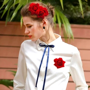 Elegant red fabric rose hair clip and brooch set worn by a model in a garden setting