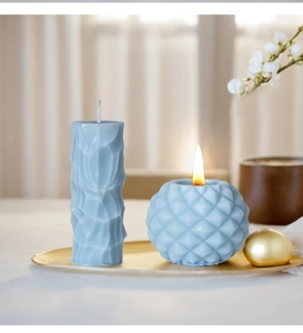 Light blue geometric column and sphere candles on golden tray with warm home decor
