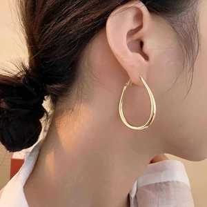 Elegante minimalistische vergoldete U-förmige Creolen an einem weiblichen Modelohr