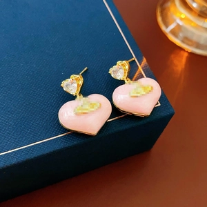 Detailed view of pink heart earrings with gold metal trim and cosmic planet logo