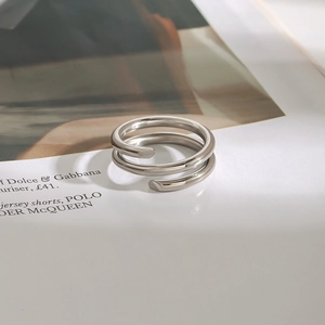 Détail macro d'une bague ouverte à double spirale en acier poli sur fond minimaliste
