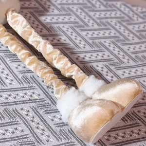 Detail of plush champagne velvet fabric and faux fur trim on a Christmas doll ornament