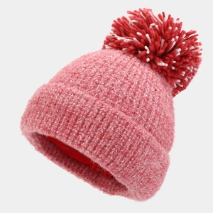 Detailed close-up of thick pink knit beanie with a fluffy red and white pompom topper