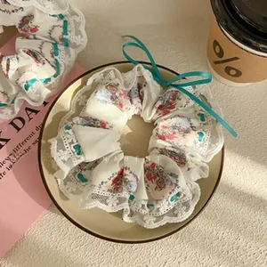 Close-up of floral scrunchie with lace edges and a green ribbon bow detail