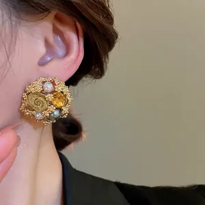 Elegant gold flower earrings with white and grey pearls and yellow crystals on model