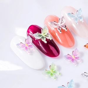 Detailed view of 3D colorful resin butterfly nail charms with glitter on various nails