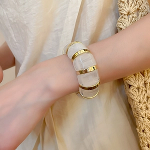Macro detail of acrylic marble resin bracelet with gold metal accents on model