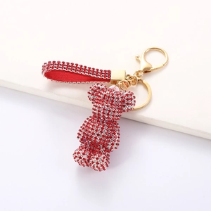 Detail of red rhinestone bear keychain with gold lobster clasp and ribbon on white pedestal