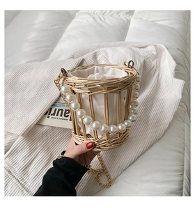 Detailed close-up of woven bucket bag featuring pearl handle and secure drawstring liner
