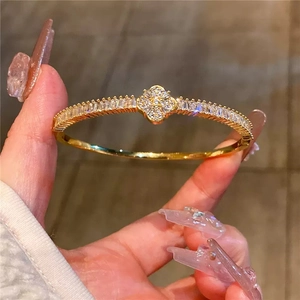 Elegant gold open cuff bracelet with sparkling zircon studded four leaf clover charm