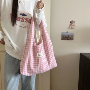 Detail of pink plaid knit tote bag with white woven label showing texture and soft fabric
