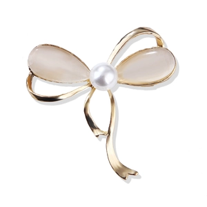 Elegant gold bow brooch with cat-eye gemstones and a large white pearl center