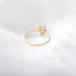 Detailed macro shot of a gold ring featuring a logo design with pink and purple crystals
