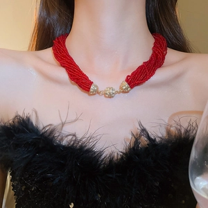 Detail view of multi-strand red bead necklace with a gold diamond-encrusted sphere clasp
