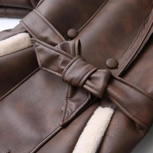Close-up of dark brown leather jacket with cream fur lining and bow belt detail
