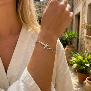 Silver Ankh cross bracelet on female wrist with natural outdoor European resort style