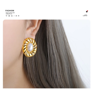 Détail de boucles d'oreilles vintage dorées à spirale avec perle et zircons