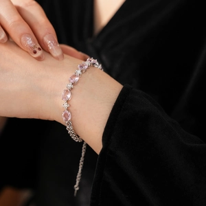 Close-up of a silver zircon bracelet with pink oval stones on a woman's wrist