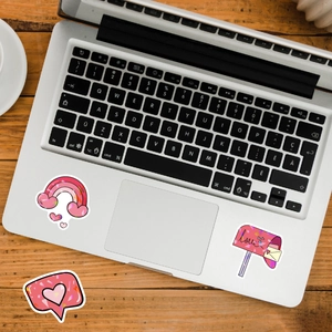 Macro view of holographic heart stickers and rainbow decals on a silver laptop keyboard