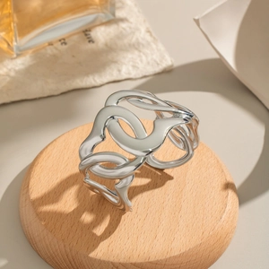 Macro detail of a thick wavy silver stainless steel cuff on a wooden base