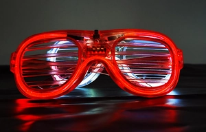 Macro shot of red LED shutter glasses glowing on a reflective black surface
