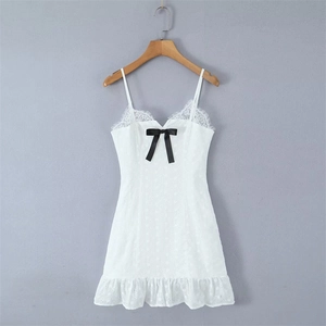 Detail of white lace mini dress featuring V-neckline with eyelash lace and black bow