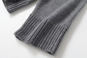 Close-up of gray knit fabric with detailed ribbing on the sleeve cuffs and hemline