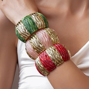 Close-up of three wide elastic bracelets with gold textured metal and marble resin blocks