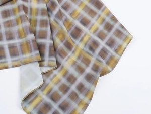 Détail du tissu à carreaux marron et gris montrant l'ourlet roulé et la texture légère