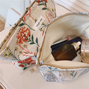 Detailed view of dandelion floral makeup bags showing jacquard fabric and interior capacity