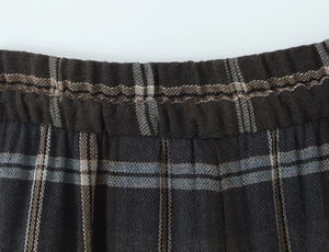 Detail of high-waisted elastic band on dark plaid trousers with thick knit texture