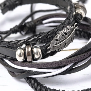 Detail of multilayer leather bracelet featuring a silver feather charm and metal beads