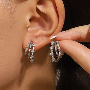 Macro shot of silver triple-layered C-shaped earrings with sparkling white zircons