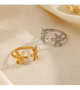 Detailed view of gold and silver flower open rings on soft beige textured fabric