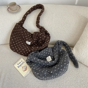 Close-up of plush teddy fleece crossbody bags with floral pattern and brand label
