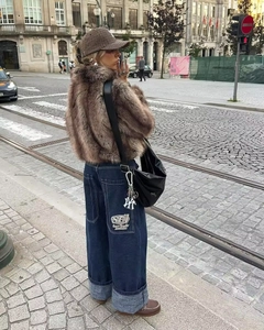Dettaglio di giacca in ecopelliccia con jeans larghi a risvolto in stile street urban