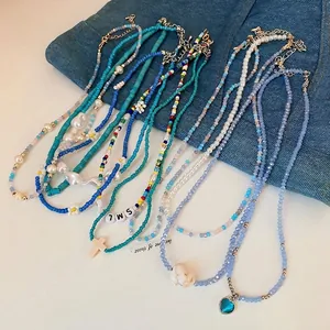 Bohemian pearl and bead heart necklace with blue pendant on denim background